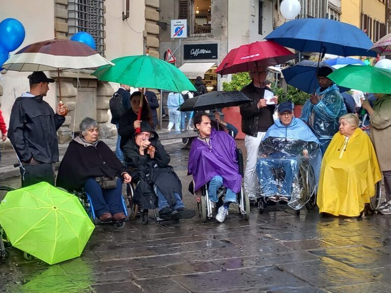 Alcune delle persone, disabili e non, che hanno partecipato al presidio di protesta promosso dall’AVI Toscana (Associazione Vita Indipendente della Toscana) sotto la pioggia, davanti al palazzo della Presidenza della Regione, a Firenze, il 5 maggio 2025.
