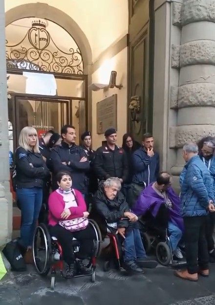 Alcune delle persone, disabili e non, che hanno partecipato al presidio di protesta promosso dall’AVI Toscana (Associazione Vita Indipendente della Toscana) sotto la pioggia, davanti all’ingresso palazzo della Presidenza della Regione, a Firenze, il 5 maggio 2025.