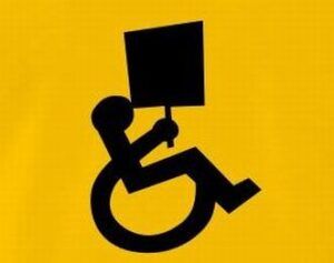 Una realizzazione grafica raffigura il logo stilizzato di una persona in sedia a rotelle che protesta con un cartello.