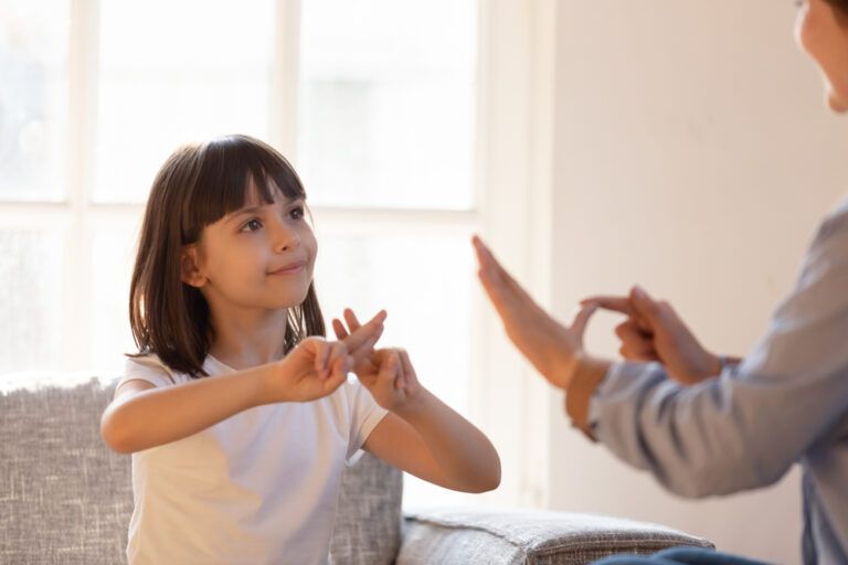 Una bambina utilizza la lingua dei segni per comunicare con un’adulta.