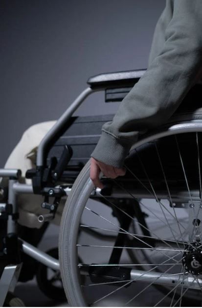 Particolare di una persona in sedia a rotelle.