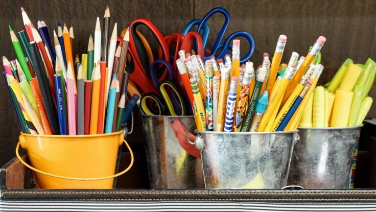 Alcuni portapenne colmi di matite colorate, forbici e evidenziatori.