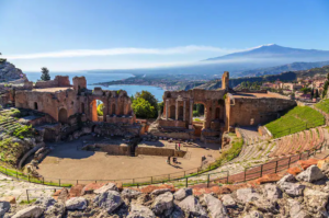 Il Teatro Antico di Taormina scavato nella roccia, con il mar Ionio e l’Etna sullo sfondo.